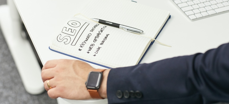Person taking notes about SEO in their notebook which is one of the ways to market your ecommerce site