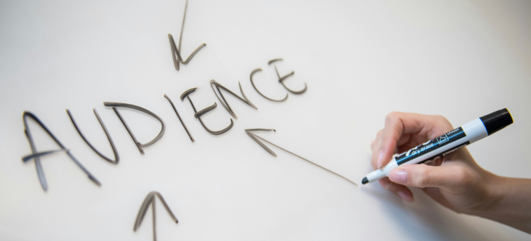 A hand with a marker emphasizes "AUDIENCE" on a whiteboard, aligning with strategies for marketing holistic approaches in drug addiction treatment.
