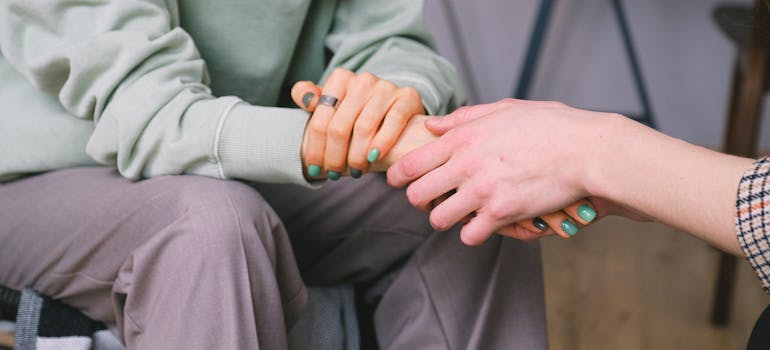a close up of a person holding a hand of another person to express support