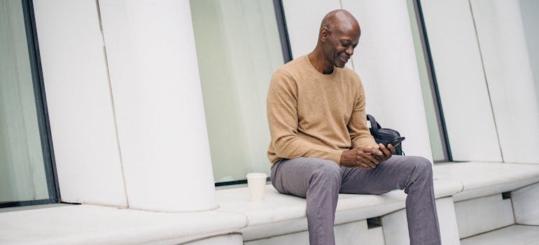 A person sitting downa and using their smarphone