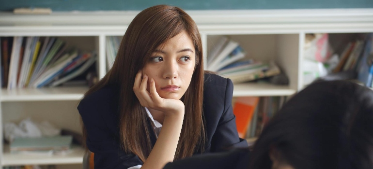 A young student in a classroom thinking about their problems