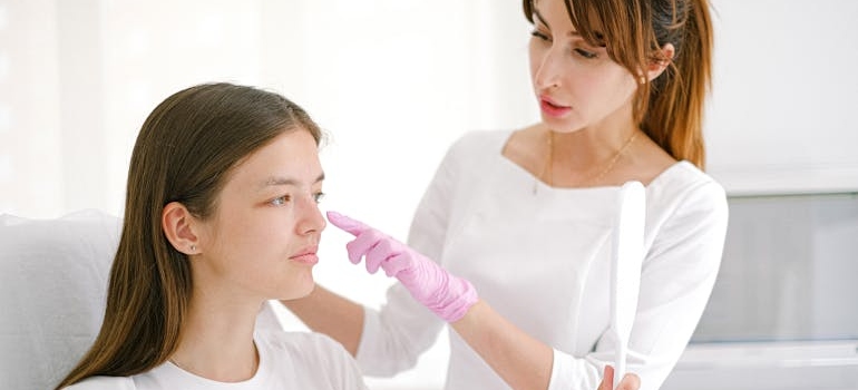A person in an aesthetic clinic looking in the mirror and listening to the surgeon