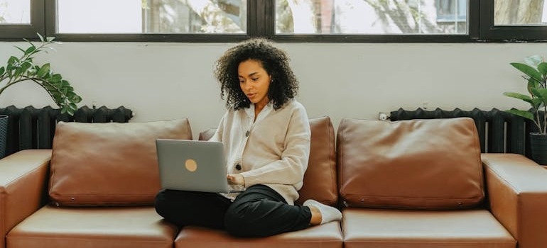 A person sitting on a sofa and using a laptop