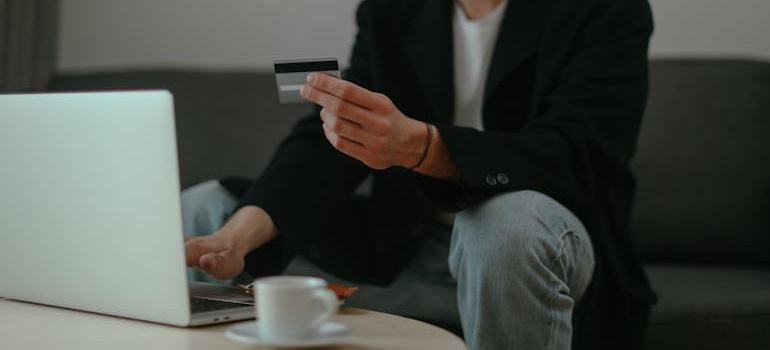 A person holding a credit card and using a laptop