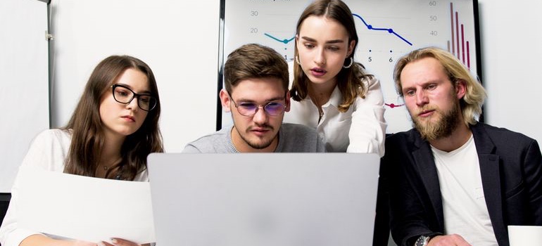 Group of professionals collaborating while reviewing information on a laptop